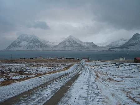 vegur, húsaþyrping, fjörður og fjöll í bakgrunni